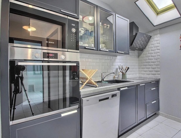 A modern kitchen with a Bosch oven, a dishwasher, and a sink with a wooden drying rack.