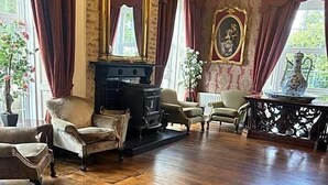 A room with a fireplace, wooden flooring, and classic furniture. - Drummond (Limavady)