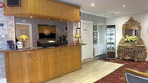 A reception area with a wooden counter, a television, and a decorative mirror. - Drummond (Limavady)