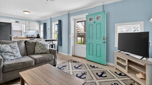 A living room with a sofa, coffee table, and a television on a wooden stand. - UNIT C: Walk to Beach/Intercoastal/Fishing Pier (Holly Ridge)