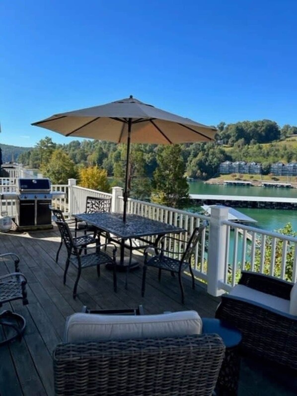 A deck with outdoor furniture, a grill, and a view of a lake. - LAKEFRONT Deerfield condo on Norris FIRST ROW steps to covered boat slip & pool (LaFollette)