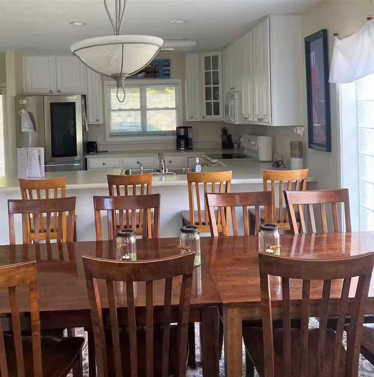 A modern kitchen with white cabinets, a central island, and wooden chairs.