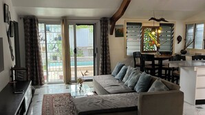 Amplia sala de estar con sofá modular, una mesa de centro de vidrio y un comedor con sillas.