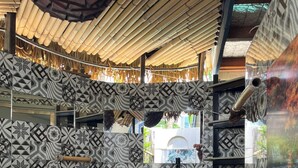 Una habitación con paredes estampadas, suelo de madera y techo con diseño de paja.
