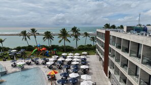 A hotel pool area with umbrellas, chairs, and a children's play structure. - Porto 2 Life Resort - GAV Resorts (Ipojuca)