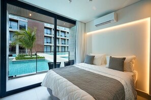 A modern hotel room with a large bed, a view of a swimming pool, and a balcony. - Porto 2 Life Resort - GAV Resorts (Ipojuca)