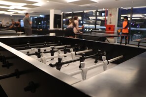 Una mesa de fútbol de mesa en un espacio interior bien iluminado con grandes ventanales.