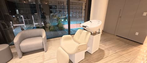 Interior moderno de clínica dental con un sillón reclinable, un lavamanos blanco y una mampara de vidrio.