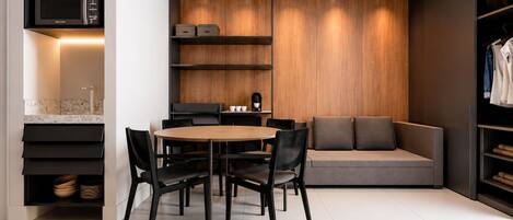 Cocina moderna con comedor, estanterías empotradas y zona de estar con sofá y cojines.