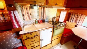A compact kitchenette with a sink, stove, and storage drawers. - "Darla" the Glamping Trailer at Ashford Lodge (Ashford)