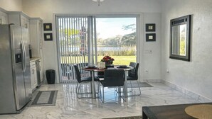 A kitchen with a refrigerator, a dining table with chairs, and a view through a sliding glass door to a backyard. - Cozy 1BR Near UCF •45 min to Disney /Acogedor 1BR Cerca de UCF •45 min de Disney (Orlando)