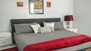 A bedroom with a bed, pillows, a red throw blanket, a nightstand, a lamp, and two framed pictures on the wall. - Cozy 1BR Near UCF •45 min to Disney /Acogedor 1BR Cerca de UCF •45 min de Disney (Orlando)