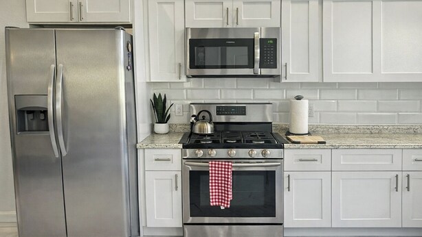 A kitchen with a stainless steel refrigerator, a microwave, a stove, and white cabinets. - Cozy 1BR Near UCF •45 min to Disney /Acogedor 1BR Cerca de UCF •45 min de Disney (Orlando)