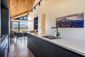 Eine moderne Küche mit einer großen Kochinsel, einem Essbereich mit Stühlen und Bergblick durch große Fenster.