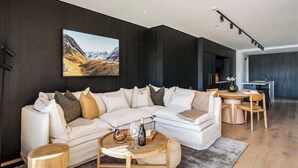 Ein modernes Wohnzimmer mit einem Ecksofa, einem runden Couchtisch und einem Essbereich mit einem kleinen Tisch und Stühlen.