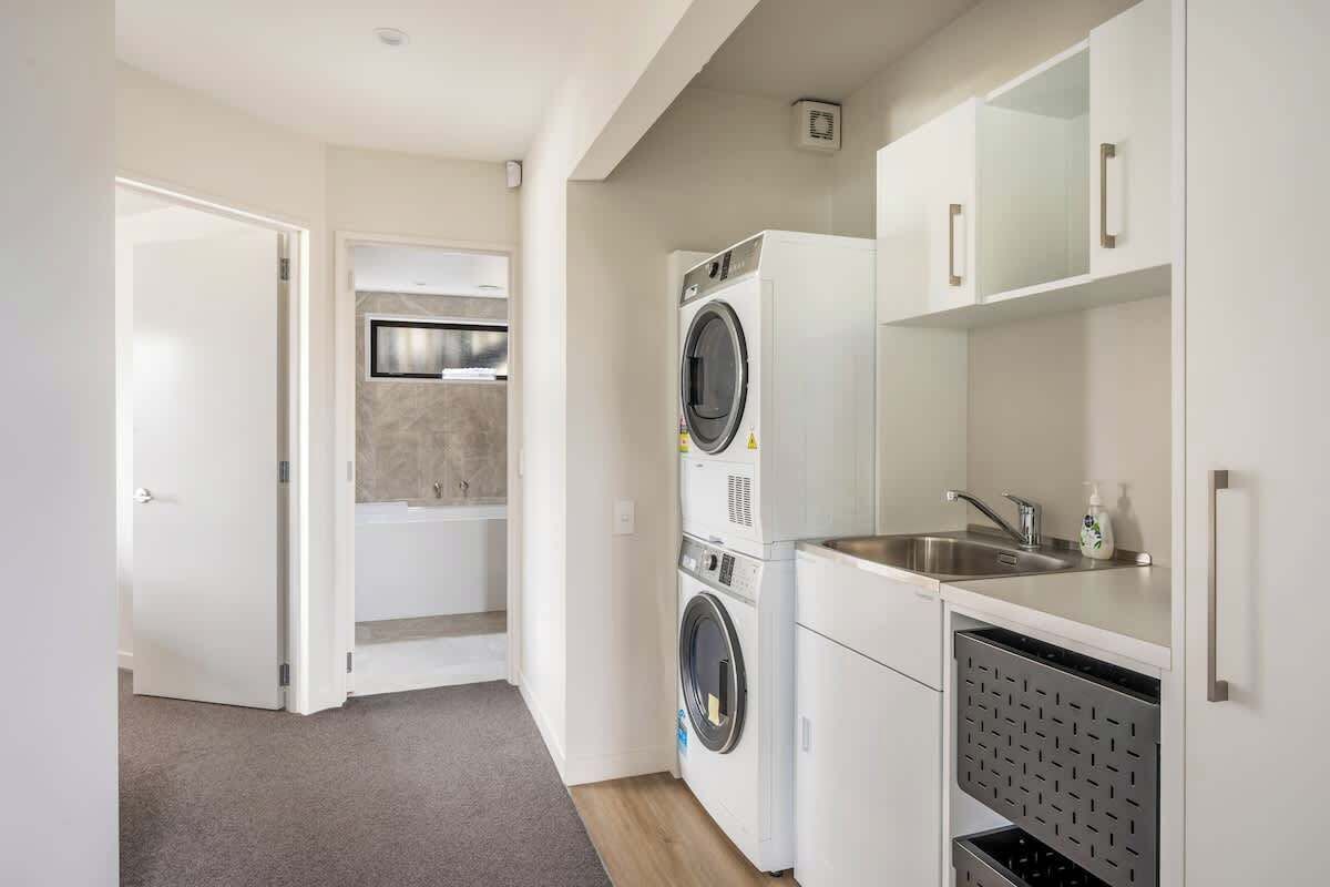 A compact laundry room with a washing machine, dryer, and sink.