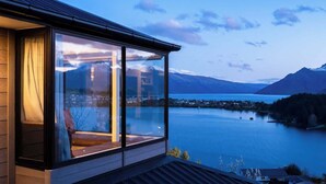 Een modern gebouw met grote ramen met uitzicht op een meer en bergen.