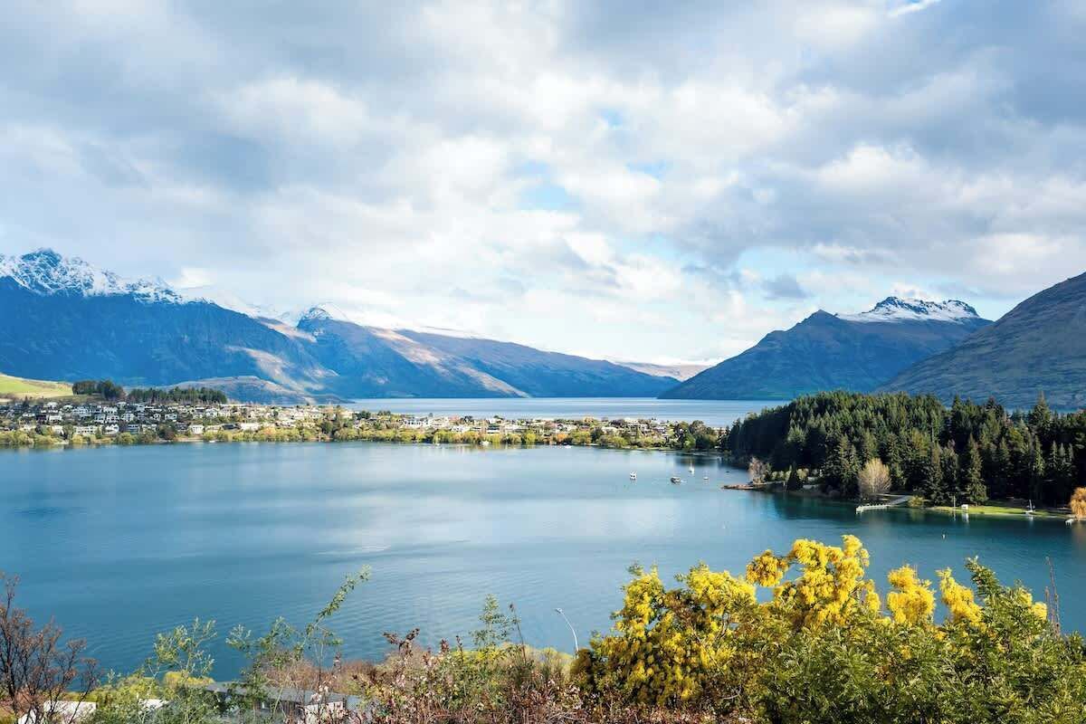 A lake with mountains in the background, surrounded by greenery and a small town.