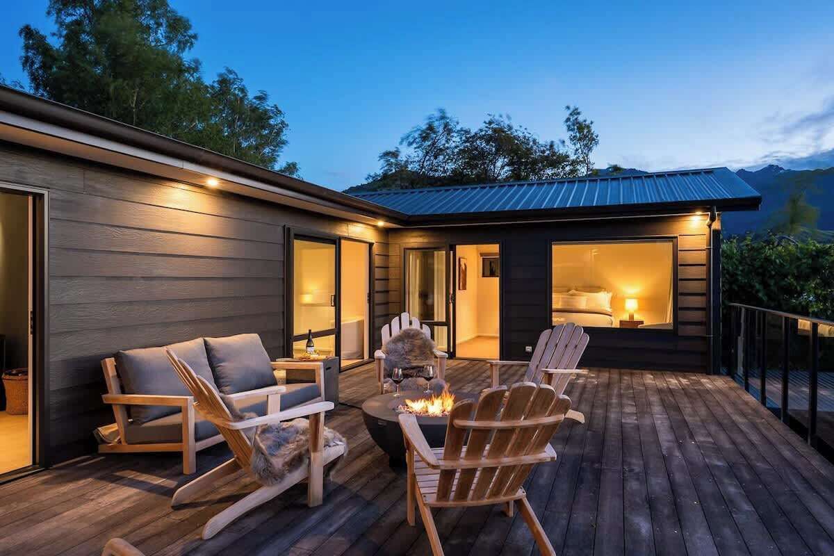 Ein modernes Haus mit Terrasse, Sitzgelegenheiten im Freien und einem Feuerkorb.