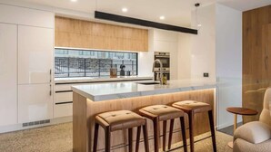 Une cuisine moderne dotée d’un îlot central, de tabourets de bar et offrant une vue sur le paysage urbain.