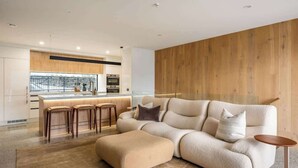 Un salon moderne avec un canapé, un pouf et des tabourets de bar.