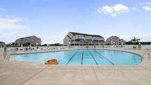 Une piscine avec des couloirs délimités, des chaises longues et un poste de surveillance pour les sauveteurs.