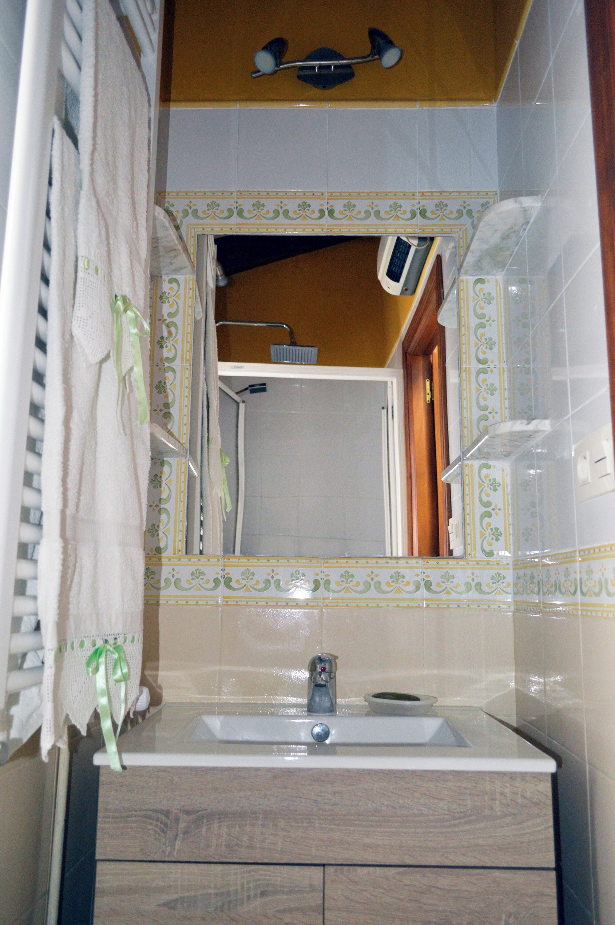 Une salle de bain équipée d’un lavabo, d’un miroir et d’un espace douche.