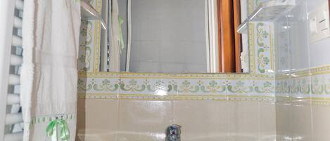 Une salle de bain équipée d’un lavabo, d’un miroir et d’un espace douche.