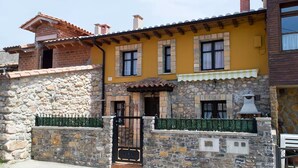 Un bâtiment à deux étages, doté d’une façade en pierre, d’un niveau supérieur jaune et d’un portail noir.