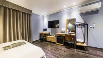 Una habitación de hotel con cama, escritorio, silla, televisor y armario.
