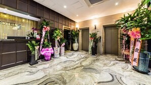 A hotel reception area with a marble floor, reception desk, potted plants, and a wall-mounted information sign. - Wol Hotel Seoul (Seoul)
