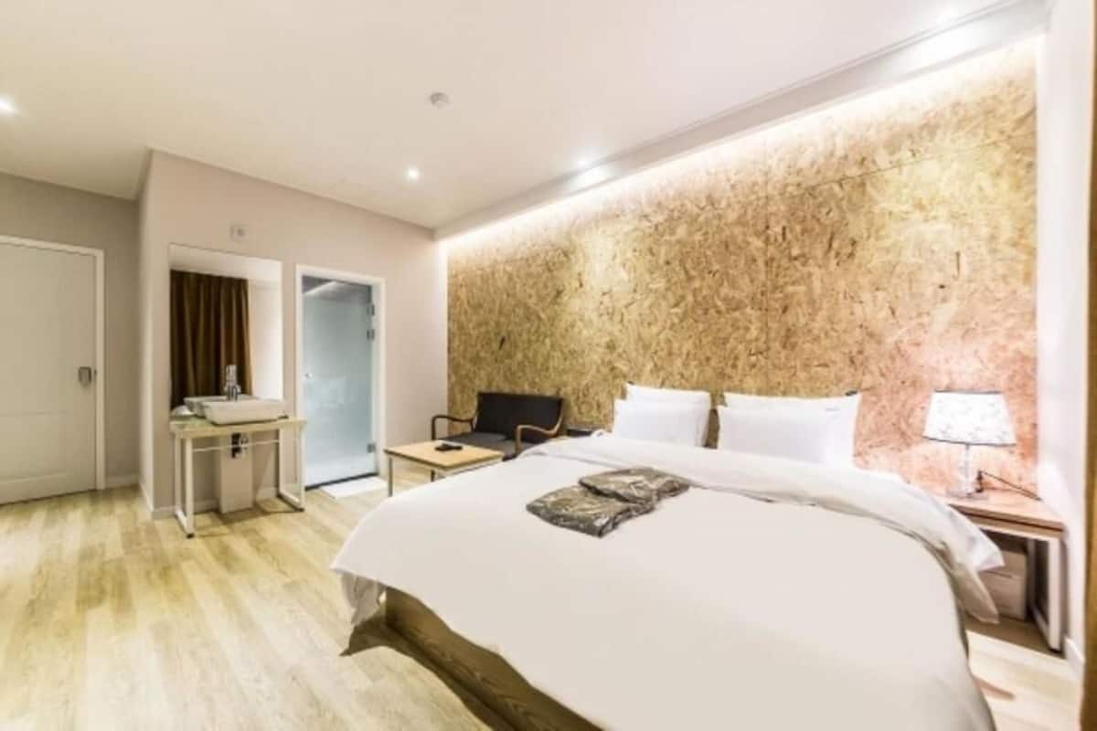 Una habitación de hotel con cama, mesita de noche, lámpara y escritorio con silla.