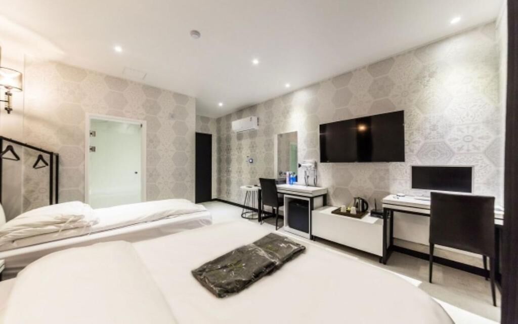 Ein modernes Hotelzimmer mit Bett, Schreibtisch, Stuhl, Fernseher und Duschbereich.