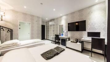 Ein modernes Hotelzimmer mit Bett, Schreibtisch, Stuhl, Fernseher und Duschbereich.