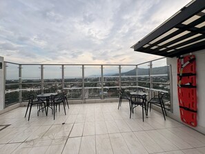 A balcony with a city view, tiled floor, and outdoor furniture.