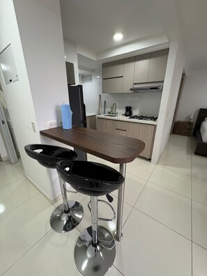 A modern kitchen with a dining area, including a bar stool and a table.