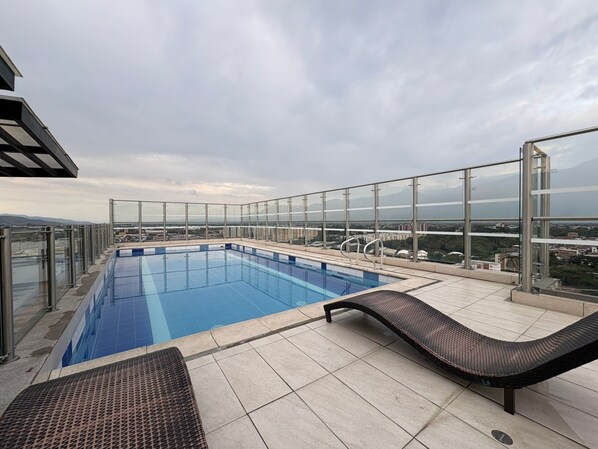 A rooftop infinity pool with glass railings and lounge chairs.