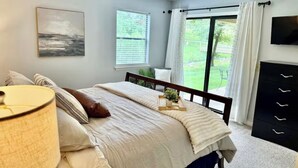 Un dormitorio con cama, ventilador de techo, ventana, televisor y vista al exterior.