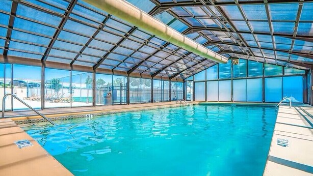 Una piscina interior con techo de cristal, agua cristalina y vistas al exterior.