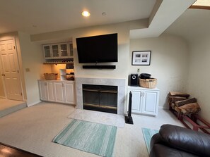 A living room with a fireplace, television, and white cabinets.