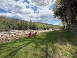 A river with rocks, a grassy area, and trees.