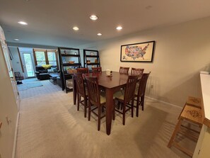 A dining area with a wooden table and chairs, a bookshelf, and a framed map on the wall.