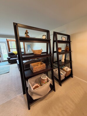 Two dark wooden shelves with baskets and a clock.