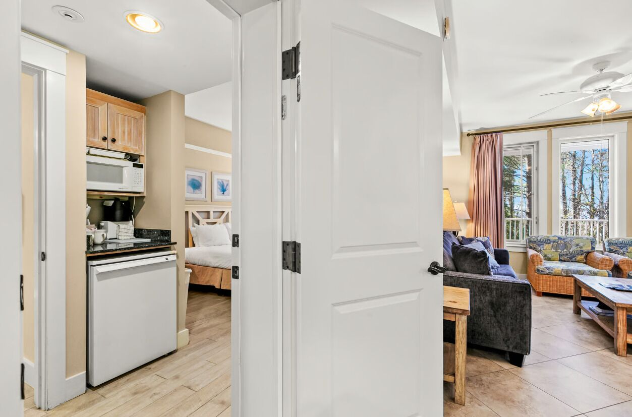Un espace de vie compact comprenant un coin cuisine, un coin repas et un espace détente avec vue sur l’extérieur.
