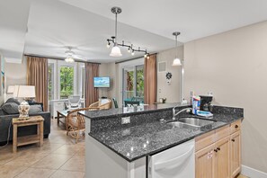 A modern kitchen with a granite countertop, a built-in dishwasher, and a coffee maker. - Market Street Inn 232/234 - Emerald Escape (Miramar Beach)