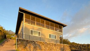 Une maison à deux étages avec des fondations en pierre et un balcon.