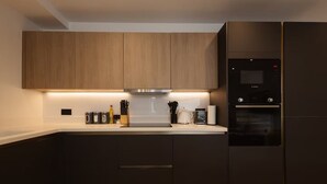 A modern kitchen with wooden cabinets, a built-in oven, and a coffee maker. - Central Leeds 1-bed Apartment Near Train Station (Leeds)