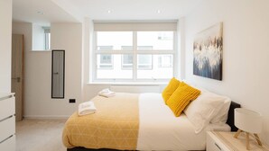 A bedroom with a bed, a window, a painting, and a nightstand. - Central Leeds 1-bed Apartment Near Train Station (Leeds)