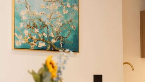 A dining area with a table, chairs, a vase with flowers, a painting on the wall, and a kitchen area with a sink and cabinets. - Central Leeds 1-bed Apartment Near Train Station (Leeds)