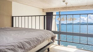 Une chambre à coucher avec un lit, une vue sur la mer et une balustrade de balcon.